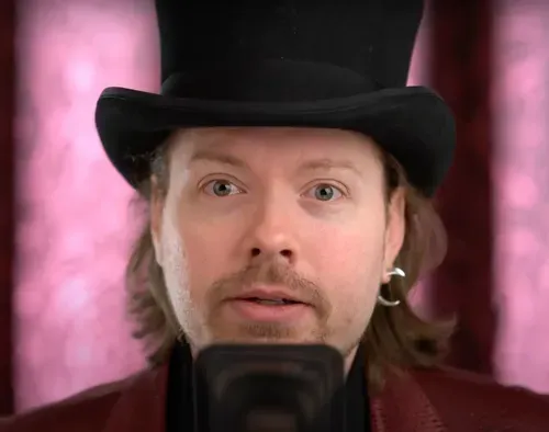 Richard Heart, wearing a top hat and speaking into a microphone