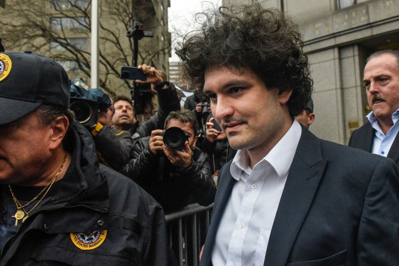 Sam Bankman-Fried, dressed in a suit without a tie, walking out of a New York courtroom.