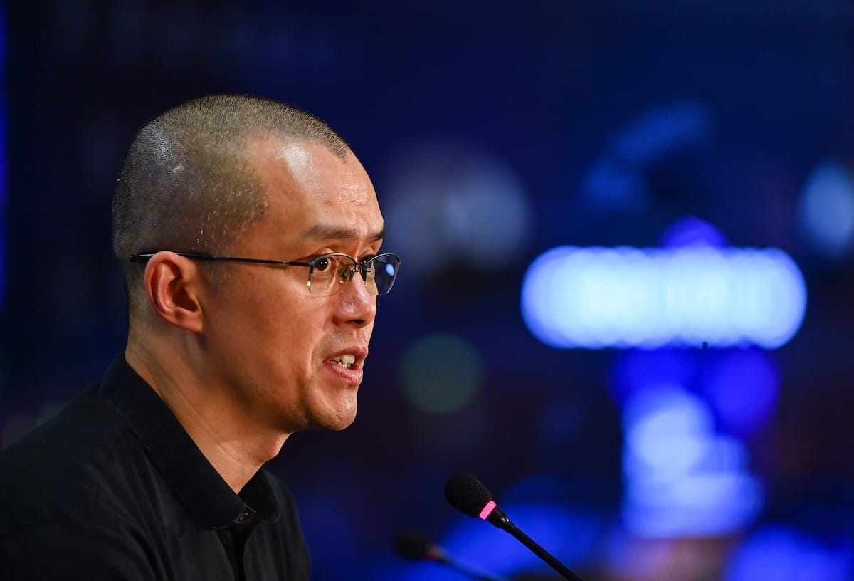 Changpeng Zhao speaking into a microphone, photographed from the side