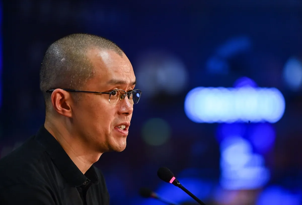 Changpeng Zhao speaking into a microphone, photographed from the side